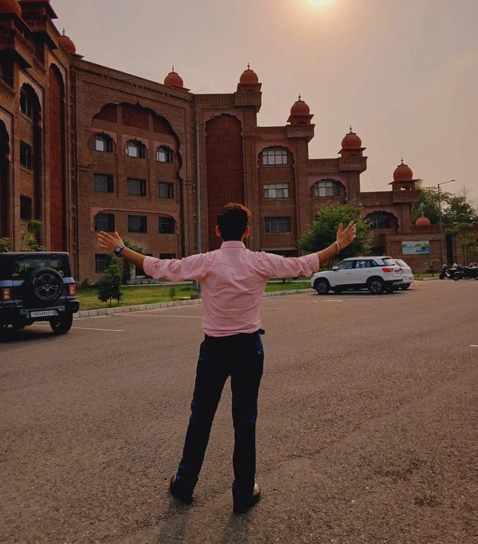 Jaspreet from behind, arms open, facing the university campus